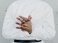 a man in a white jacket with his hands in his pockets