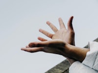 a person's hands reaching up to the sky